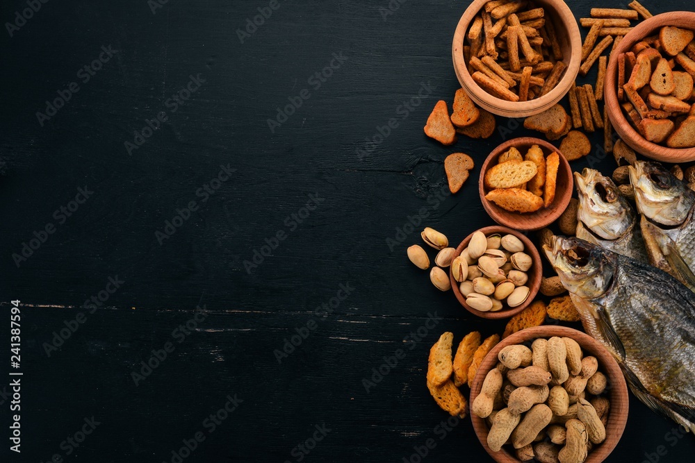 A selection of beer and snacks. Light beer, dark beer, live beer. On a black wooden background. Free space for text. Top view.