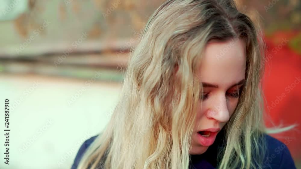 A young attractive girl is standing on the street, she is tired and yawns. A young attractive girl is standing on the street, she is tired and yawns.