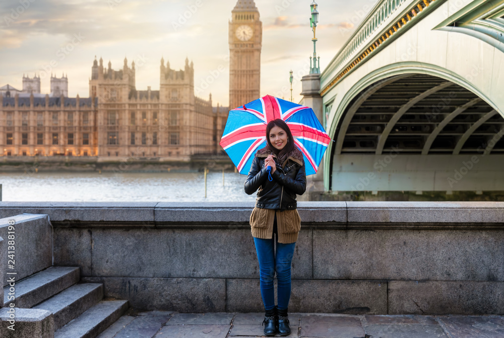 Fototapeta premium Atrakcyjny turysta z Brytyjską flaga na parasolowym stojaku przed Big Ben w Westminster, Londyn