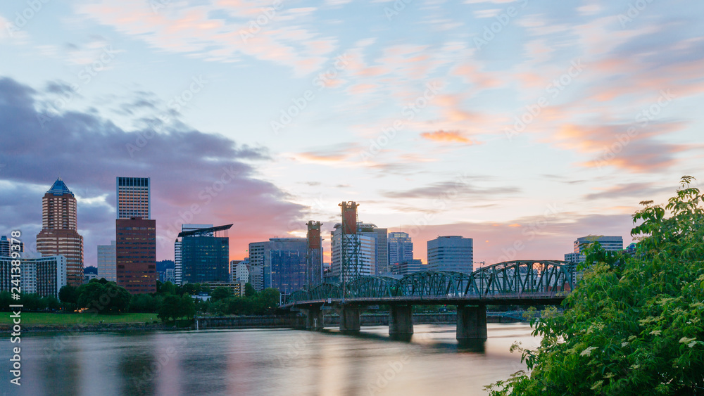 Hawthorne Bridge over Willamette River at sunset with skyline of downtown Portland, USA