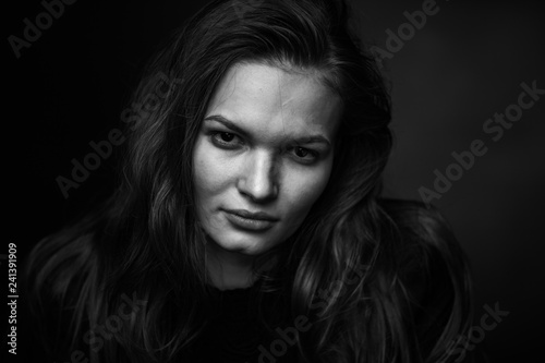 Dramatic black and white portrait of a beautiful girl on a dark background