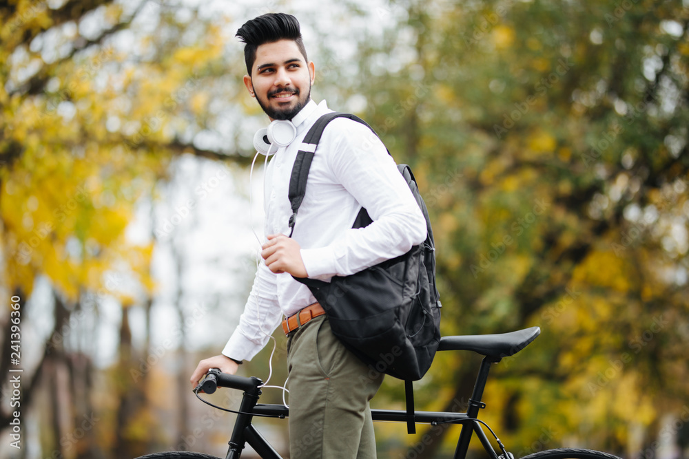 Casual handsome asian businessman with handsbag going to work by bicycle