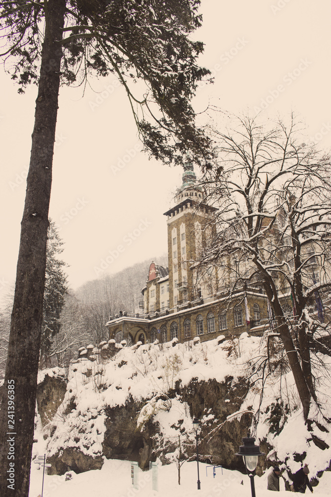 Castle in winter forest in Lillafured, Miskolc, Hungary. Snowy forest and rocks around historical luxury palace. Travel and winter vacation in Europe. Hungarian architecture. Lillafred landmark. 