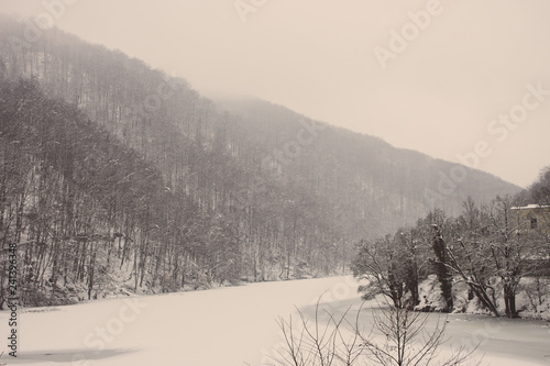 Frozen winter lake with cold forest in Lillafured, Miskolc, Hungary. Lake with ice and snowy mountain. Winter landscape. Travel in Hungary. Winter weather concept. Snowy mountain in frosty fog.