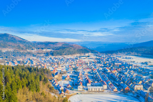 Croatia, Delnice, Gorski kotar, panoramic view of town center from drone in winter, mountain landscape in background, houses covered with snow 