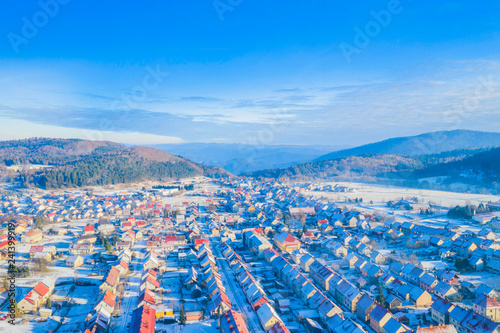 Croatia, Delnice, Gorski kotar, panoramic view of town center from drone in winter, mountain landscape in background, houses covered with snow 