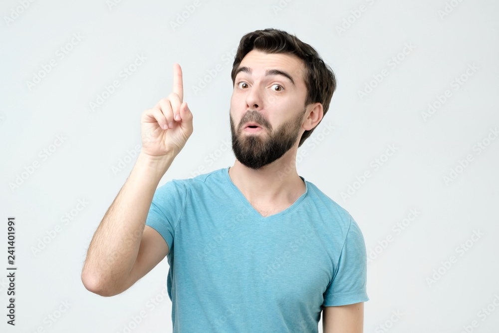 Experienced young man showing index fingers up, giving advice Experienced young man showing index fingers up, giving advice