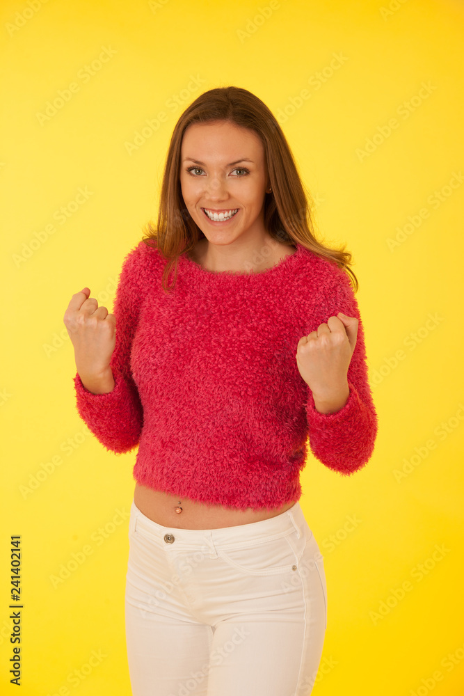Beautiful happy young woman in pink sweater over vibrant yellow background Beautiful happy young woman in pink sweater over vibrant yellow background