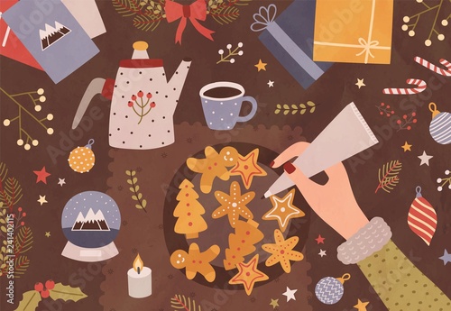 Christmas greeting card template with hand holding pastry bag and decorating cookies, cup of tea, teapot and festive seasonal decorations lying on table. Colorful vector illustration in flat style.