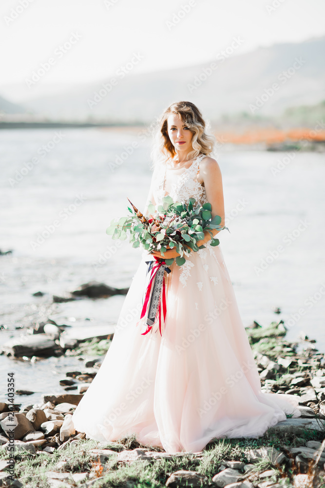 Portrait of stunning bride with long hair posing with great bouquet near river Portrait of stunning bride with long hair posing with great bouquet near river