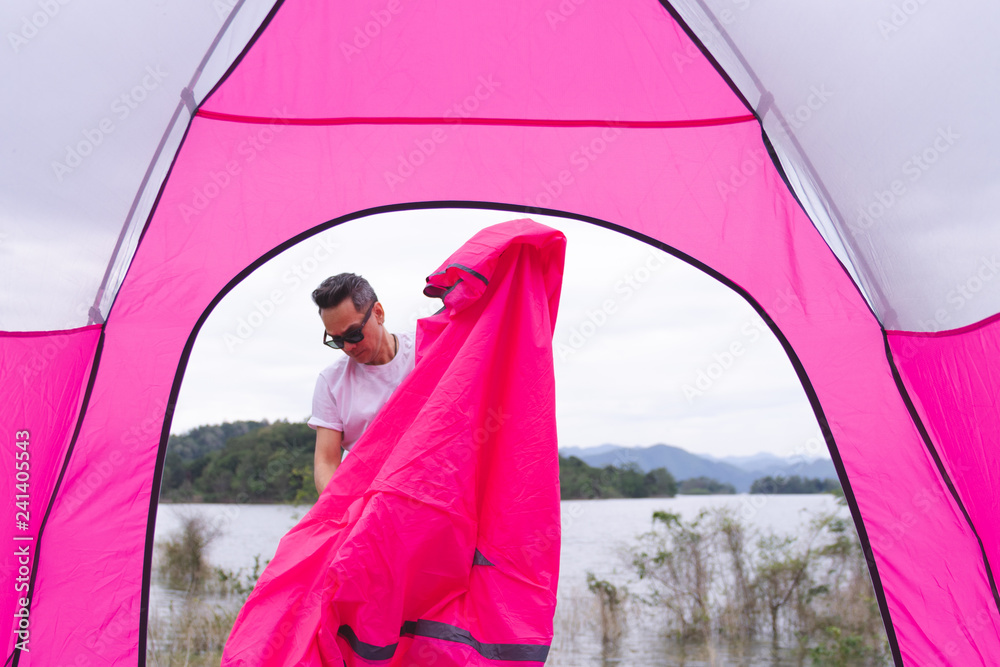 an Asian man in white t shirt setting pink tent at campground