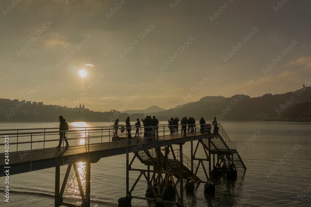 Obraz premium Atardecer en el muelle. Gente mirando al sol