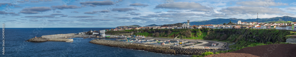 Panoramic View of colorful quay and port of village Rabo de Peixe with boats, church and lighthouse in Sao Miguel, the largest of the Azores Islands, Portugal. Sunny cloudy day
