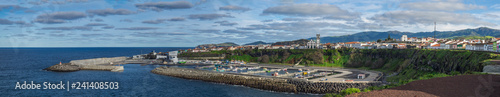Panoramic View of colorful quay and port of village Rabo de Peixe with boats, church and lighthouse in Sao Miguel, the largest of the Azores Islands, Portugal. Sunny cloudy day