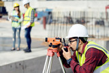 surveyor engineer with theodolite at construction site during surveying work.engineer and architect working at construction site with blueprint