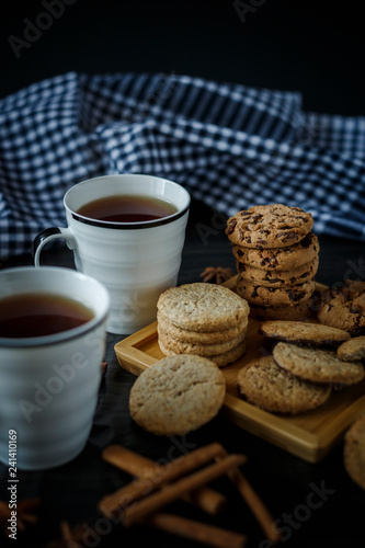 Two cups of tea and various cookies on dark wooden background