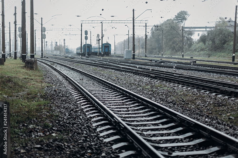 Obraz premium railway tracks. transportation roads and platform with carriage. foggy rainy atmosphere on railroad.