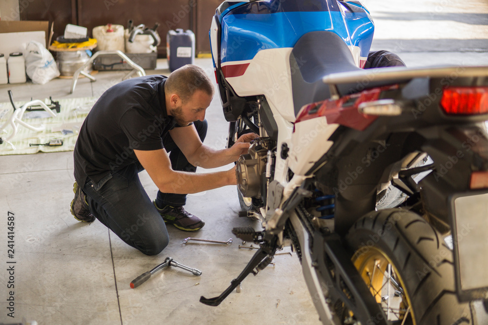 Mechanic working on motorcycle in workshop Mechanic working on motorcycle in workshop