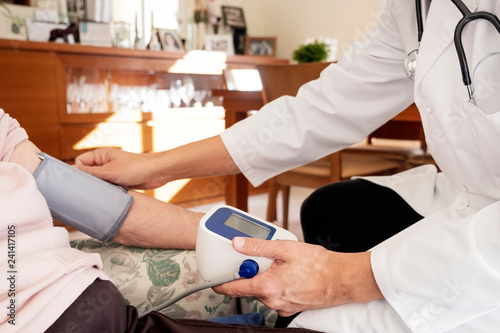 doctor measuring the blood pressure of a senior photo