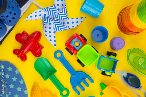 Chilldren's beach equipment and toys on bright yellow background. Children summer vacations concept. photo