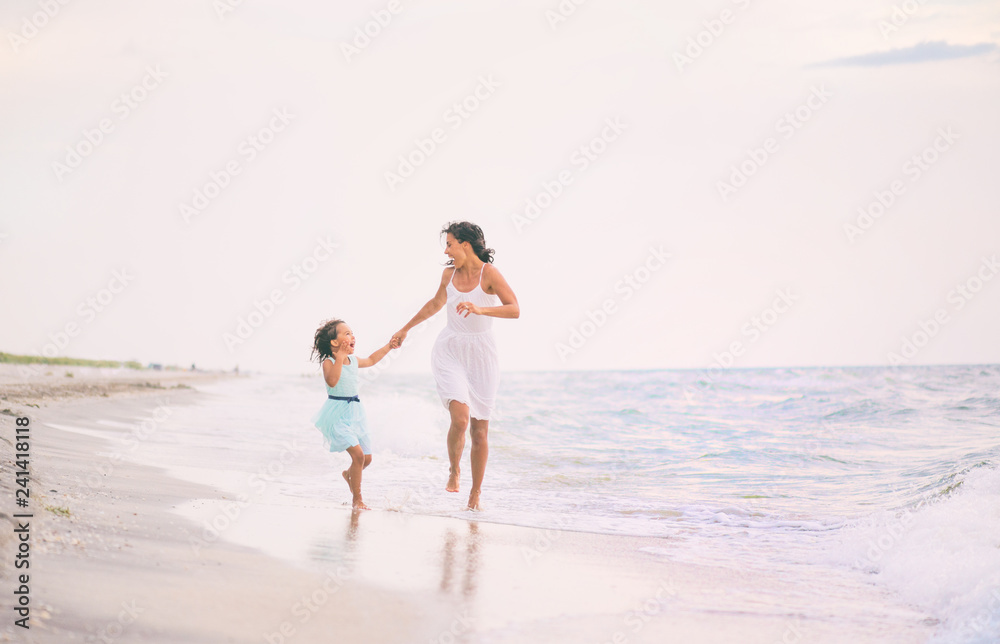 Mother and her daughter runing and having fun on the beach