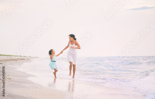 Mother and her daughter runing and having fun on the beach