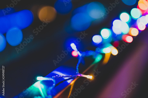 string of multicolored fairy lights on house terrace with bokeh effect