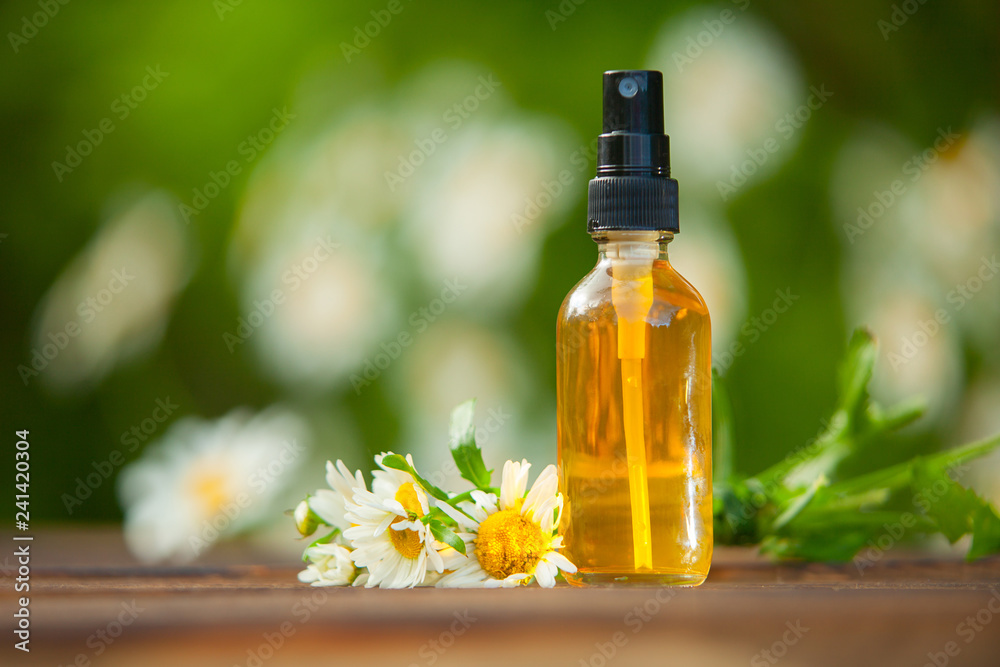 Essence of flowers on table in beautiful glass bottle Essence of flowers on table in beautiful glass bottle