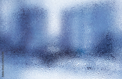 wet glass in drops of rain. wet background of blue.the texture of the wet glass