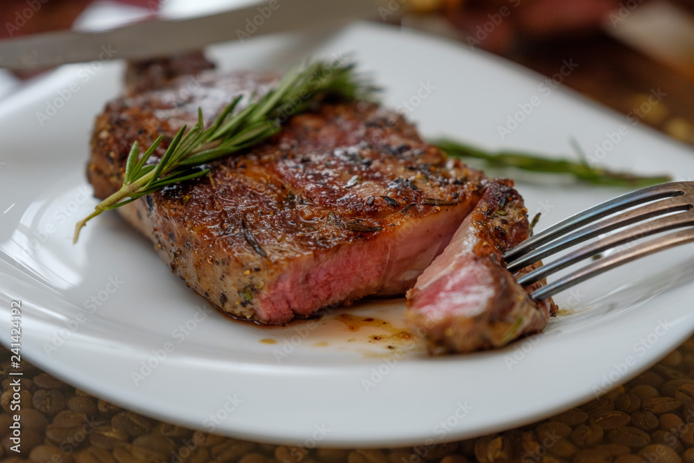 Beef steak with a sprig of rosemary on a plate. Image. Beef steak with a sprig of rosemary on a plate. Image.
