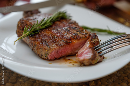 Beef steak with a sprig of rosemary on a plate. Image.