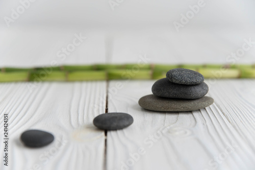 Canvas Print Pyramids of gray zen pebble meditation stones with green bamboo leaves and on wooden background