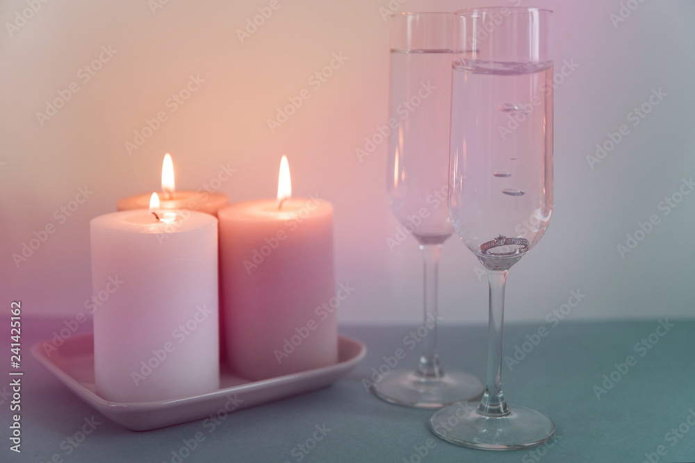 Marriage proposal and love concept for Valentine`s day with wedding or engagement ring with brilliant. Glasses of champagne and romantic candles in the restaurant Marriage proposal and love concept for Valentine`s day with wedding or engagement ring with brilliant. Glasses of champagne and romantic candles in the restaurant