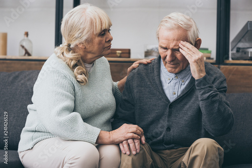 retired woman sitting near senior husband with headache photo