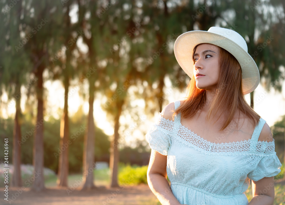 Portrait fashion ,Beautiful woman wearing white dress and hat posing at the flower parks.