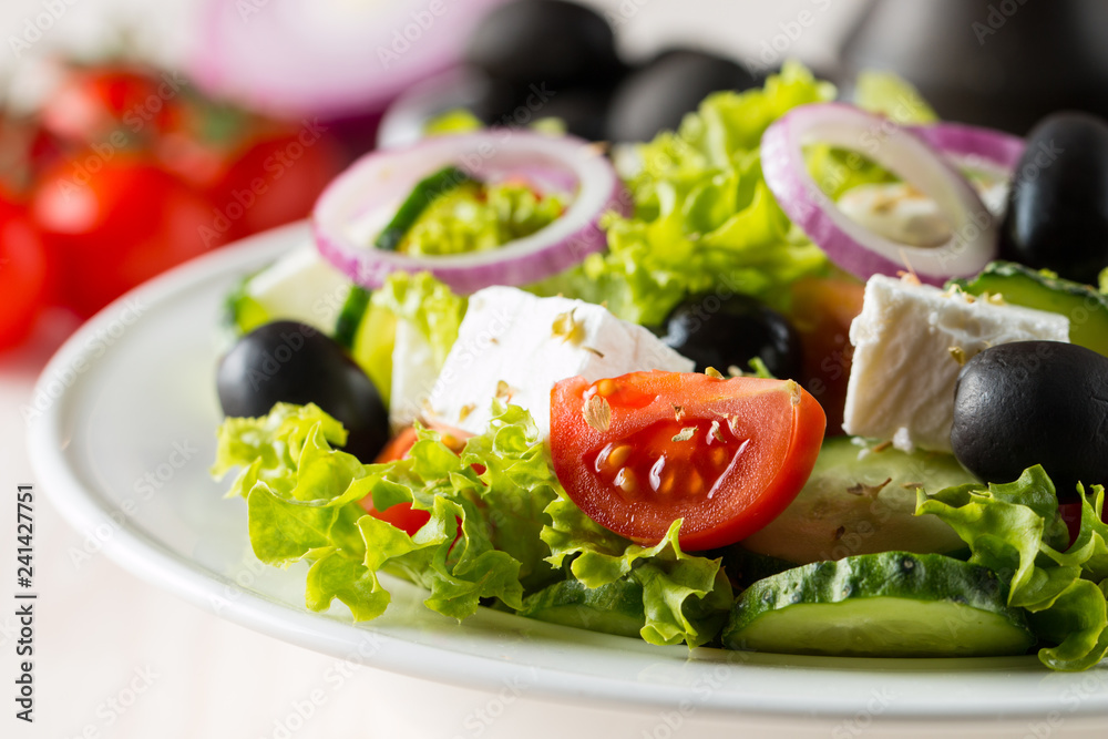 Fresh Greek salad with delicious ruccola, spinach, cabbage, arugula, feta cheese, red onion and cherry tomato on wooden background. Oil, salt and pepper. Healthy and diet food concept. Fresh Greek salad with delicious ruccola, spinach, cabbage, arugula, feta cheese, red onion and cherry tomato on wooden background. Oil, salt and pepper. Healthy and diet food concept.