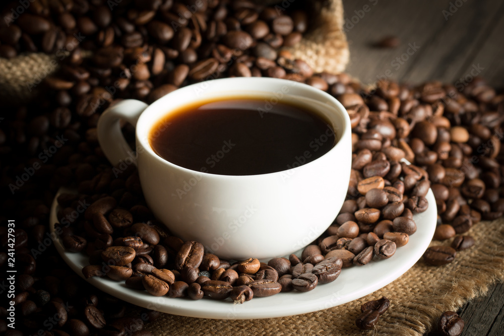 Coffee cup and beans on a rustic background. Coffee Espresso and a piece of cake with a curl. Cup of Coffee and coffee beans on table. Coffee cup and beans on a rustic background. Coffee Espresso and a piece of cake with a curl. Cup of Coffee and coffee beans on table.