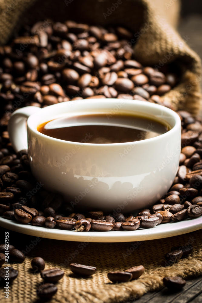 Coffee cup and beans on a rustic background. Coffee Espresso and a piece of cake with a curl. Cup of Coffee and coffee beans on table. Coffee cup and beans on a rustic background. Coffee Espresso and a piece of cake with a curl. Cup of Coffee and coffee beans on table.