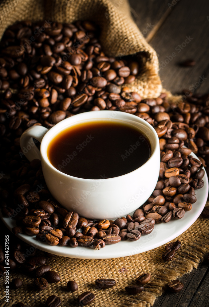 Coffee cup and beans on a rustic background. Coffee Espresso and a piece of cake with a curl. Cup of Coffee and coffee beans on table. Coffee cup and beans on a rustic background. Coffee Espresso and a piece of cake with a curl. Cup of Coffee and coffee beans on table.