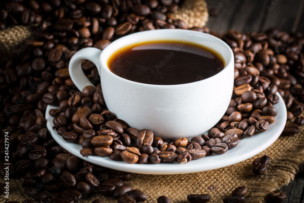 Coffee cup and beans on a rustic background. Coffee Espresso and a piece of cake with a curl. Cup of Coffee and coffee beans on table. Coffee cup and beans on a rustic background. Coffee Espresso and a piece of cake with a curl. Cup of Coffee and coffee beans on table.