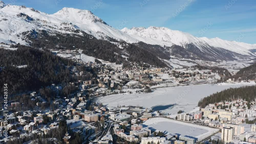 Aerial view of St. Moritz in winter, famous ski resort town in Swiss Alps mountains, snow on slopes, sunny day with blue sky - landscape panorama of Switzerland, Europe