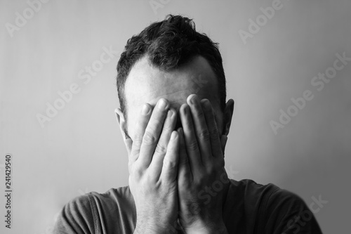 Εκτύπωση καμβά man from grief and sadness covers his face with his hands, black and white photo