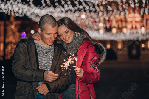 Happy couple with sparklers in winter city night