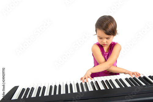 Little girl playing at piano isolated on white