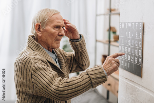 old man looking at calendar and touching head