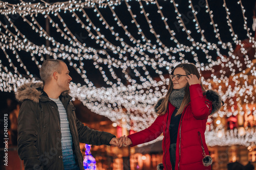 Young couple holding hands at night during winter holidays