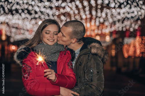 Young couple with sparklers in winter city night