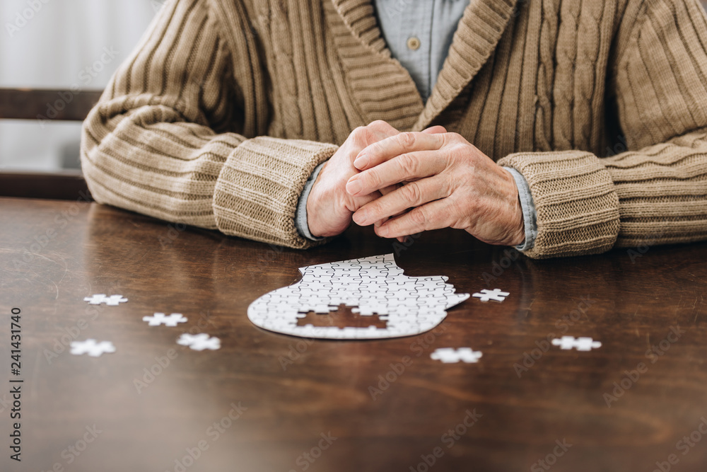 cropped view of retired man playing with puzzles on table - obrazy, fototapety, plakaty 