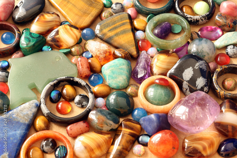 Close up of semi precious tumbled gemstones, cabachons, rings and pendants