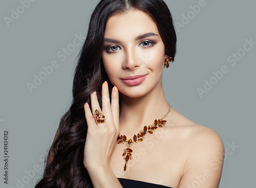 Beautiful brunette woman with makeup and amber ring, necklace and earrings